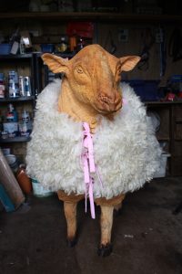chainsaw carved sheep wearing jacket