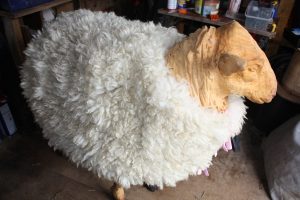 chainsaw carved sheep with felted fleece jacket